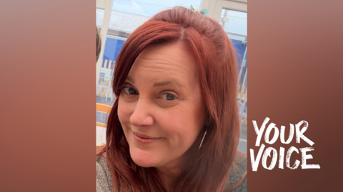 A woman with red hair. She is smiling. 