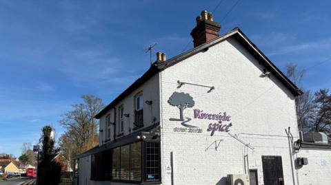 A white building that reads 'Riverside Spice' and a phone number on the side 
