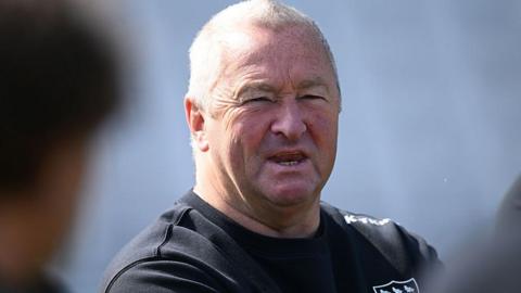 Paul Farbrace in dark Sussex sweatshirt addresses players who are out of focus in foreground