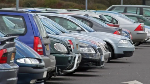 Image shows a row of cars parked in a car-park