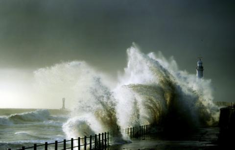 A huge wave crashes against the coast at Seaburn, Sunderland, with a lighthouse partially obscured by the water