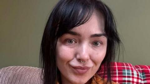 A woman with brown hair stares at the camera 