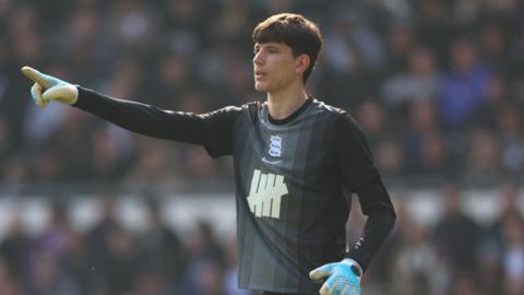 A photo of James Beadle directing his team-mates while playing for Birmingham City in their black goalkeeping kit and blue gloves in March