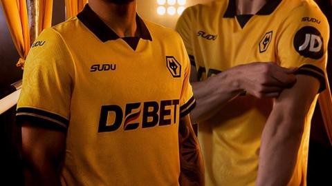 An image of two players zoomed in on the Wolves 2025-26 home kit which is gold with a black trim on the sleeves and a black collar