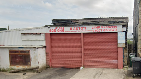 Google Maps image showing the outside of S Autos garage on Bulay Road in Huddersfield, with two large red garage doors and offices in a white building to the left.