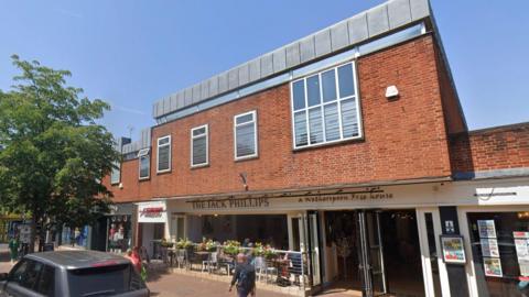 The Jack Phillips pub on the ground floor of a two-storey 1960s brick building.