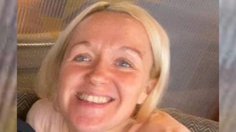 A woman with blonde hair smiles at the camera