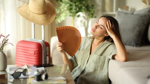 Stressed tourist suffering heat stroke during vacation in apartment - stock photo
