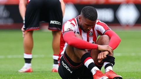 Tyrese Campbell sits on the pitch looking dejected
