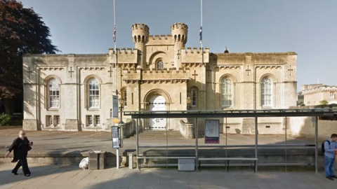 A Google Maps picture of Oxford Coroner's Court, a Grade II listed building. A bus stop stands in front of it.