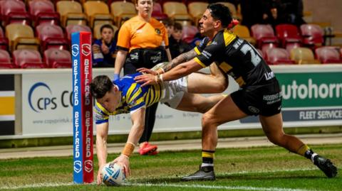 Warrington's Josh Thewlis dives to score a try inside the corner post under pressure from York's Nikau Williams