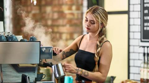 A young woman with long blond hair working in a coffee shop