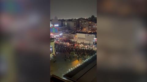 People protesting down a street at night.