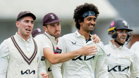 Surrey players congratulate each other after taking a wicket