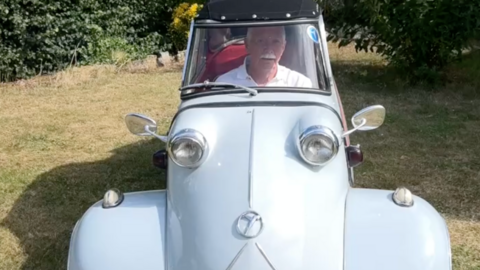 Man sitting in very small, pale blue car