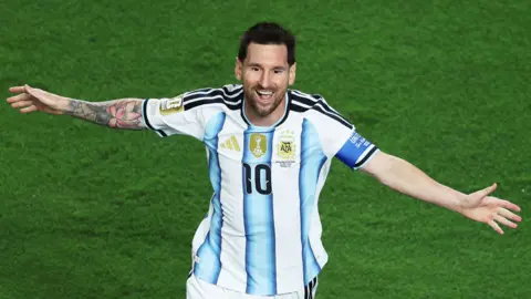 Lionel Messi with arms outstretched celebrates scoring for Argentina