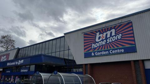 A general view of a large flat-roofed warehouse style shop with a large sign reading B&M home store & garden centre