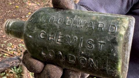An old chemist's bottle. It has the words 'Woodward Chemist London' engraved on the side of it.