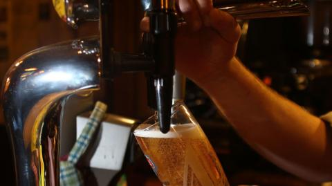 A close-up of a person pouring a pint on tap.