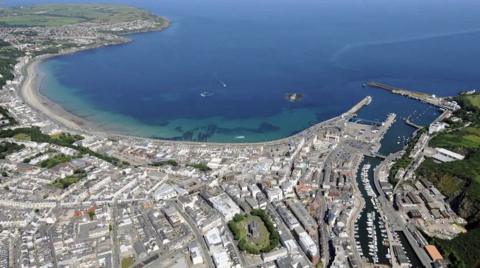 An aerial view of Douglas. It shows the sweep of the bay, with development along the shore and beyond.
