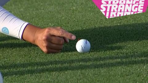 A finger pointing at a golf ball