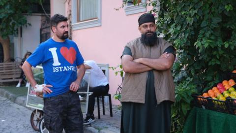 Two men stand next to each other on a street in Istanbul.