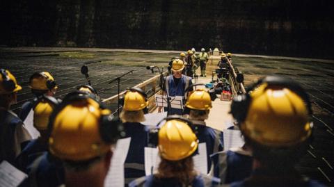 A group of people with yellow hard hats on and headphones over the top