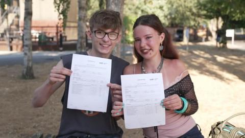 A man and a woman showing off their A-Level results.