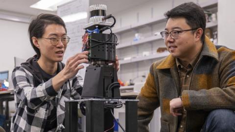 Prof Mingmin Zhao and a student look at the robot