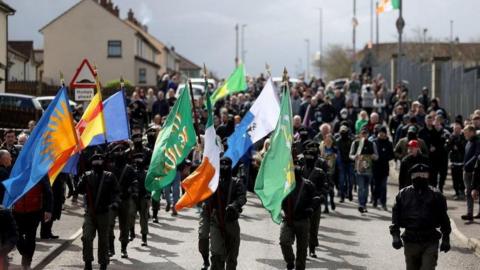 Masked men in combat uniforms take part in the dissident parade through the Creggan estate in Derry in April 2023