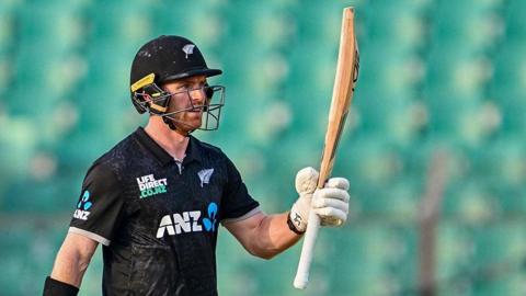 Nick Kelly raises his bat after scoring a half-century for New Zealand