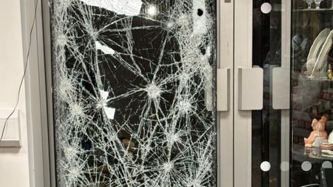 A close-up of a glass door that has been smashed repeatedly.