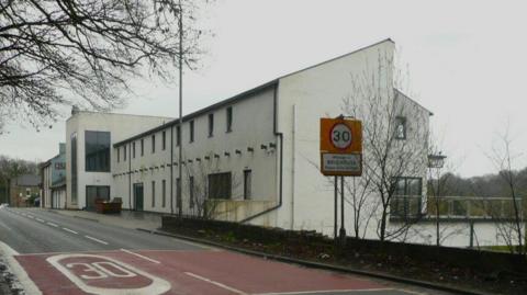 A building with a white exterior and a brown sign painted on the wall reads 'Casa'
