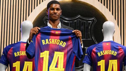 Marcus Rashford holds up a number 14 shirt