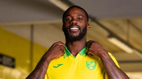 Jeffrey Schlupp in a yellow Norwich shirt with green collar