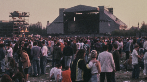 Stone Roses gig on Spike Island in Widnes in 1990. There are countless music fans standing in front of a large pyramid-shaped stage.