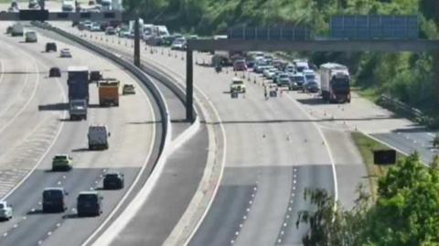 A photo from a traffic camera on the M1 showing police at the scene of a crash and a road closure in place.