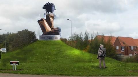 An artist's impression of the sculpture on a plinth with the words "Three Bags Full" on the side. It is on a grass mound. The bronze bags have wool sticking out of them. The black metal sheep is standing on the top bag.