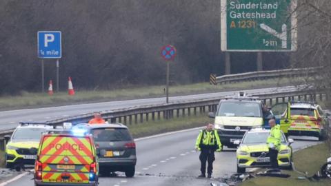 Image of the A19 closed by police. There are five police vehicles in the image and two police officers standing nearby.