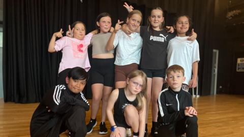 Eight children doing breakdancing classes are pulling different poses 