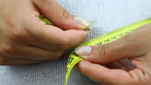A person putting a measuring tape around their waist.