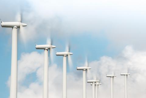 Eight fast-spinning wind turbines set against a blue sky with white and grey cloud