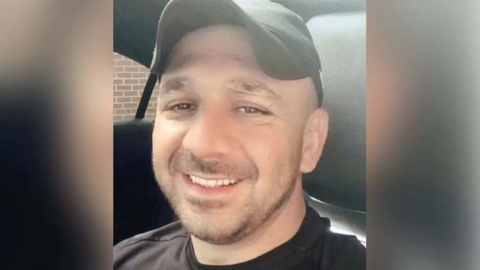 Hemawand Ali Hussein smiling into the camera. He is sat in a car with black seats and is wearing a black cap and t-shirt.