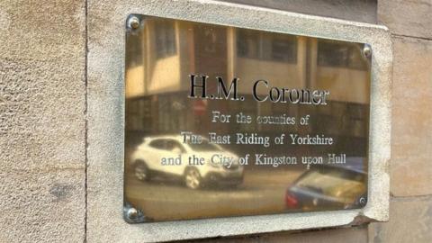 A brass plaque reading HM Coroners Court mounted on a stone wall outside Hull's coroners court.