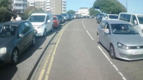 A number of vehicles can be seen, parked illegally next to double yellow lines
