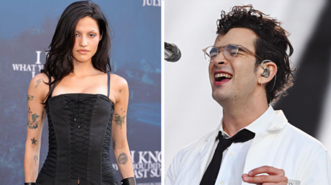 Gabbriette Bechtel on the left wears a black corset and has several tattoos on her arms. Matty Healy, right, performs on stage wearing a white lab coat and glasses.