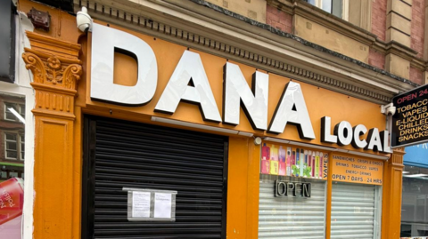 Orange-coloured signage on the shop front of Dana Local.