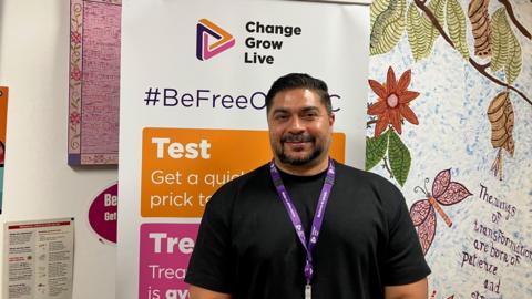 Raja Alyas smiling for the camera in front of a white and orange Aspire board