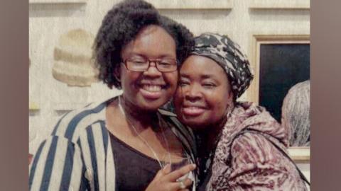 Two women with arms around each other smile for the camera. 