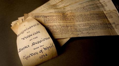 Old parchment and sheets of archival documents displayed on a table